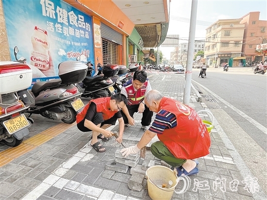 網(wǎng)格員和志愿者一同修復(fù)路面。