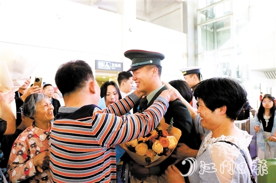 身著軍裝的返鄉(xiāng)退役士兵逐一出站，迎接他們的是鮮花與擁抱。