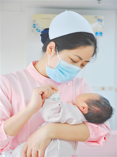 這是一雙托起生命的手。江門市中心醫(yī)院愛嬰?yún)^(qū)主管護(hù)師湯玲玲正在安撫哭鬧的寶寶。她一手環(huán)住襁褓，一手牽起寶寶的小手，動作舒緩而溫柔。在這里，生命的啼哭與溫柔的守護(hù)相遇，匯聚成世間至暖的力量。（林錦棠