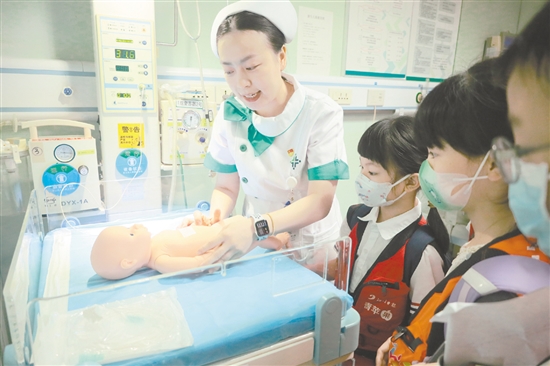 醫(yī)護(hù)人員為小記者演示新生兒輻射保暖臺(tái)的用途。