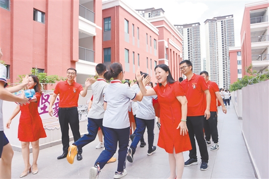蓬江區(qū)紫茶中學的領導和老師們與考生們擊掌，為他們加油、鼓勁。