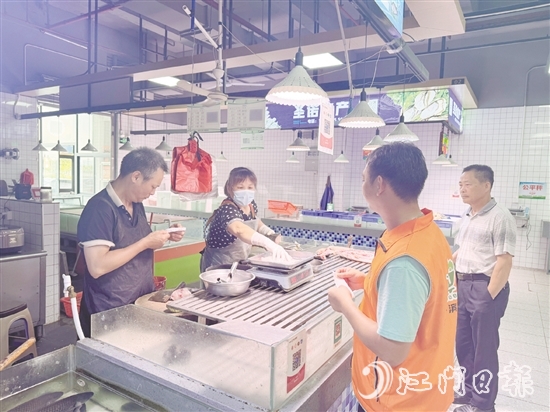 買菜易的平臺接單員李叔（橙色馬甲）正在魚攤旁等待取單。