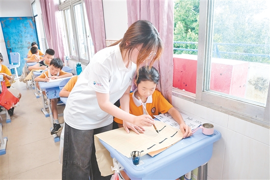 社會實踐隊隊員指導(dǎo)學(xué)生練習(xí)硬筆、軟筆書法。