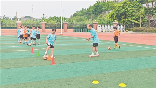 學(xué)生在教練的指導(dǎo)下學(xué)習(xí)足球技巧。