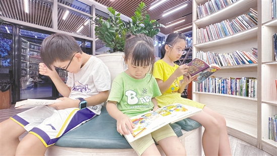 低年級(jí)學(xué)生圍坐在書架旁閱讀繪本。